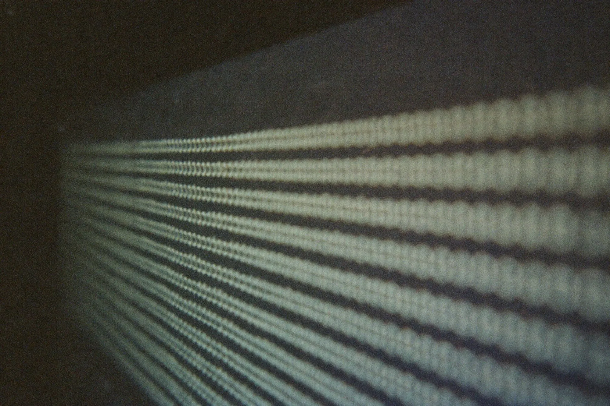 A screen surface at a shallow angle: lines of code as soft bands of light, subpixels visible